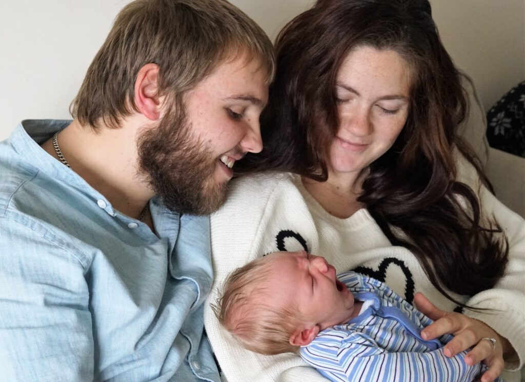 New baby yawning with man and woman smiling